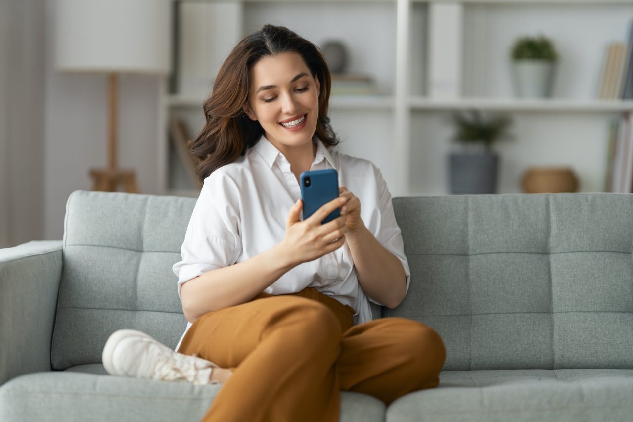 woman-is-using-a-phone-sitting-on-a-sofa.jpg
